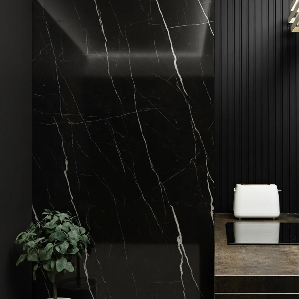 Panel WPC Alto Brillo efecto Mármol Negro Marquina instalado en la pared de cocina moderna con encimera oscura y tostadora blanca, aportando contraste y sofisticación.