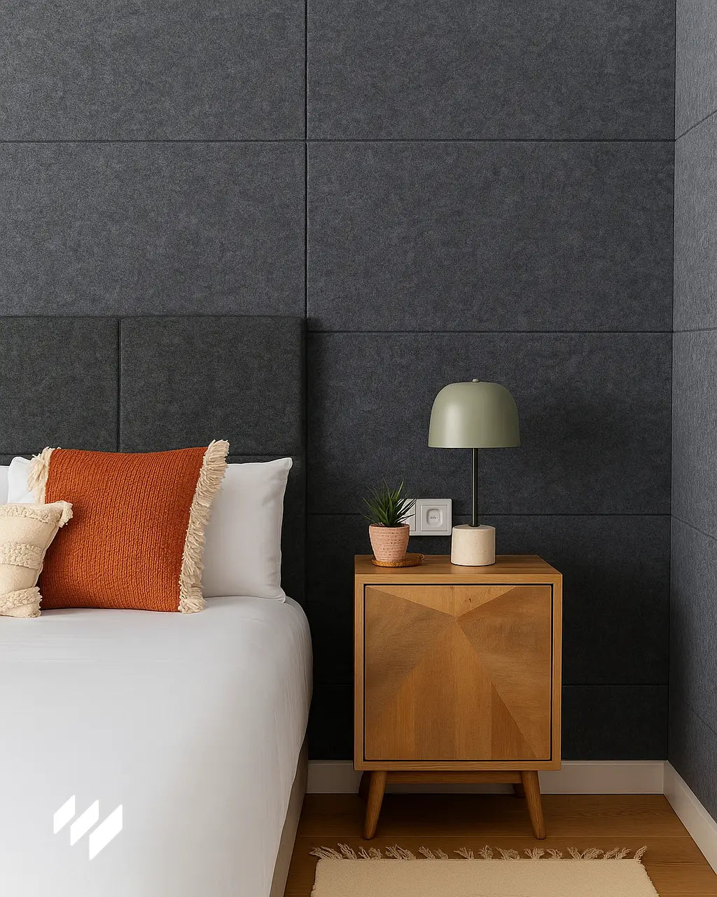 Dormitorio moderno con paneles acústicos autoadhesivos de poliéster gris instalados en la pared detrás del cabecero, aportando estilo y aislamiento sonoro. La decoración incluye una mesita de noche de madera y cojines en tonos cálidos.