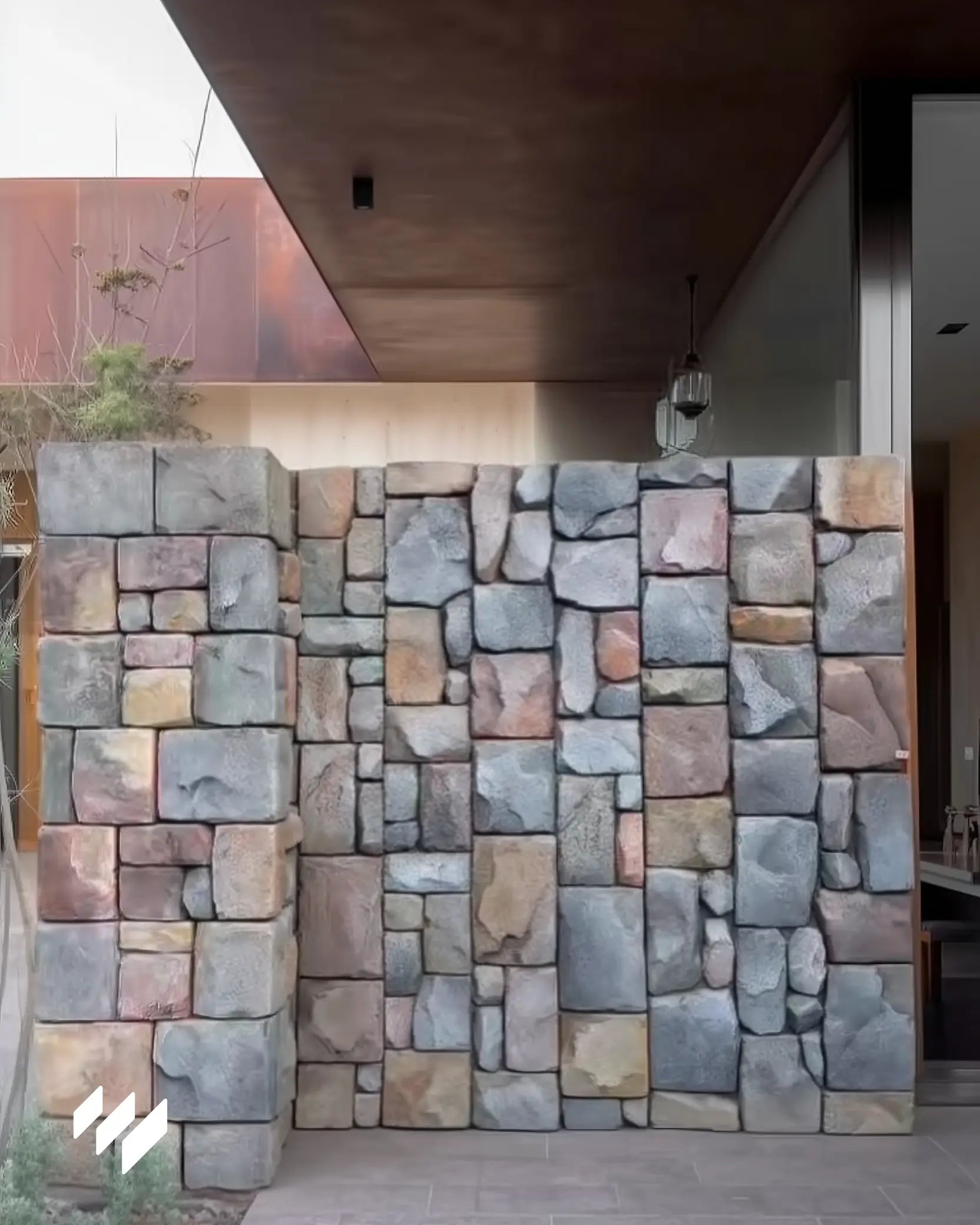 Pared exterior de casa moderna revestida con panel PU efecto piedra rústica en tonos naturales