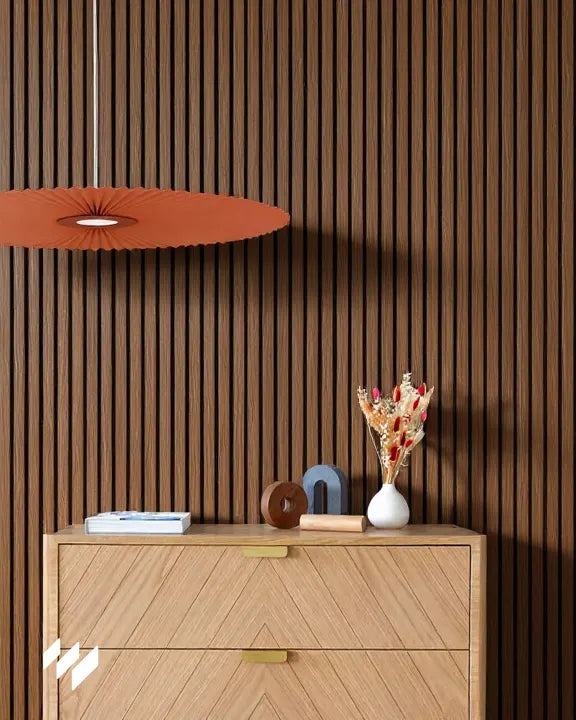 Instalación del revestimiento acústico Roble Ahumado de Revestimientos Pared en pared vertical detrás de aparador claro con decoración minimalista.