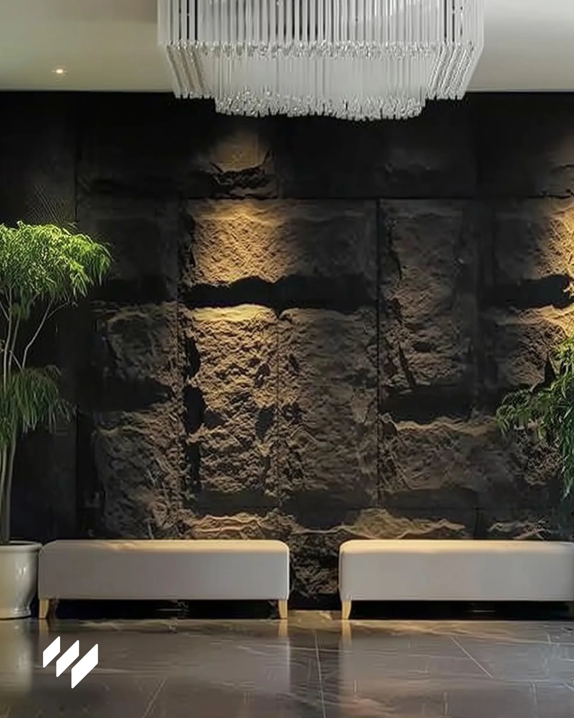 Pared decorativa con revestimiento PU efecto piedra Negro Basalto de Revestimientos Pared en un elegante lobby moderno con bancos beige y luz cálida indirecta.