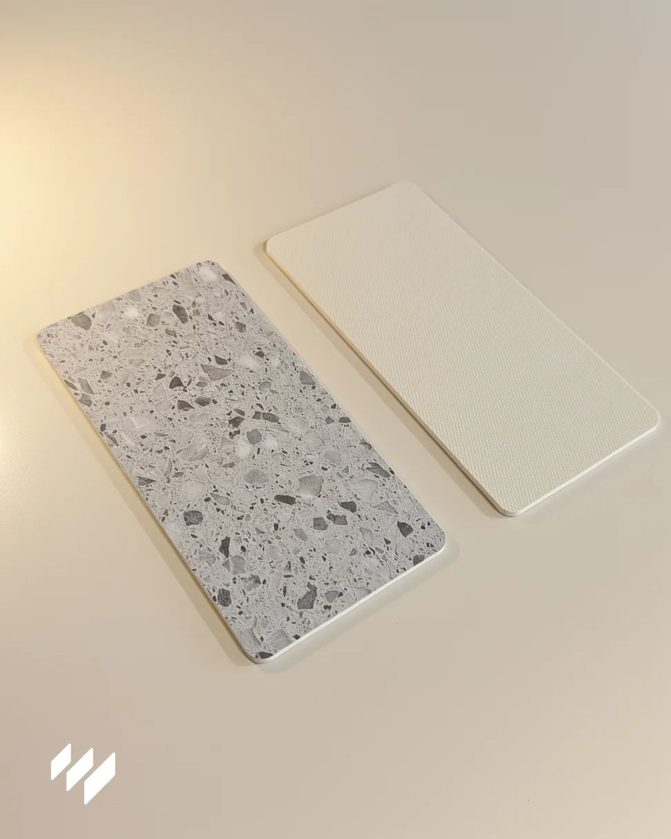 Muestras del revestimiento de pared SPC efecto terrazo gris de Revestimientos Pared, mostrando el frente decorativo y el reverso antideslizante.