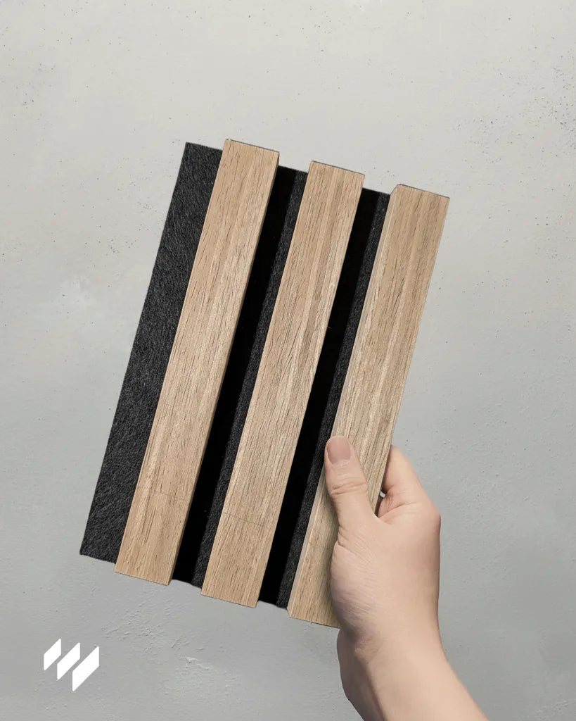 Muestra del Panel Acústico de Listones Nogal Natural sostenida con una mano, producto de Revestimientos Pared.