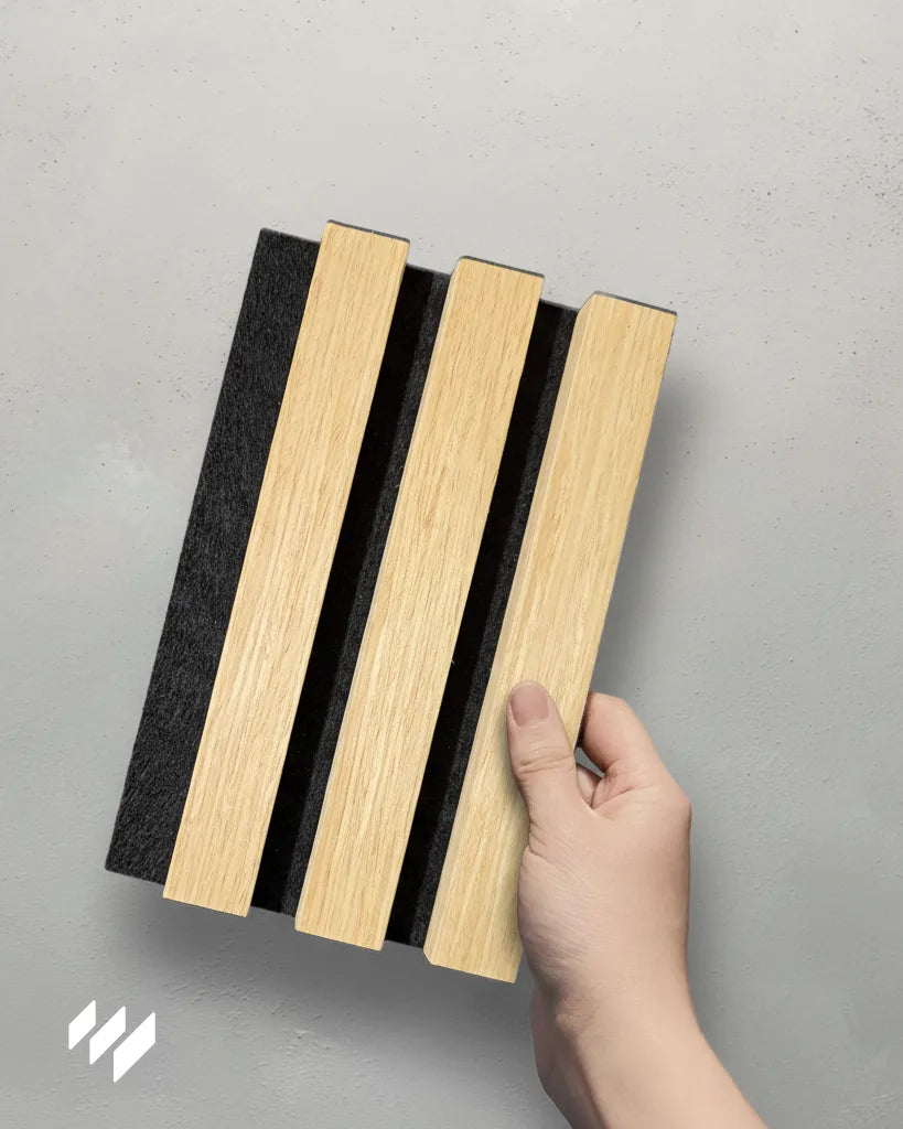 Muestra del Panel Acústico de Listones Roble Natural sostenida con una mano, producto de Revestimientos Pared.