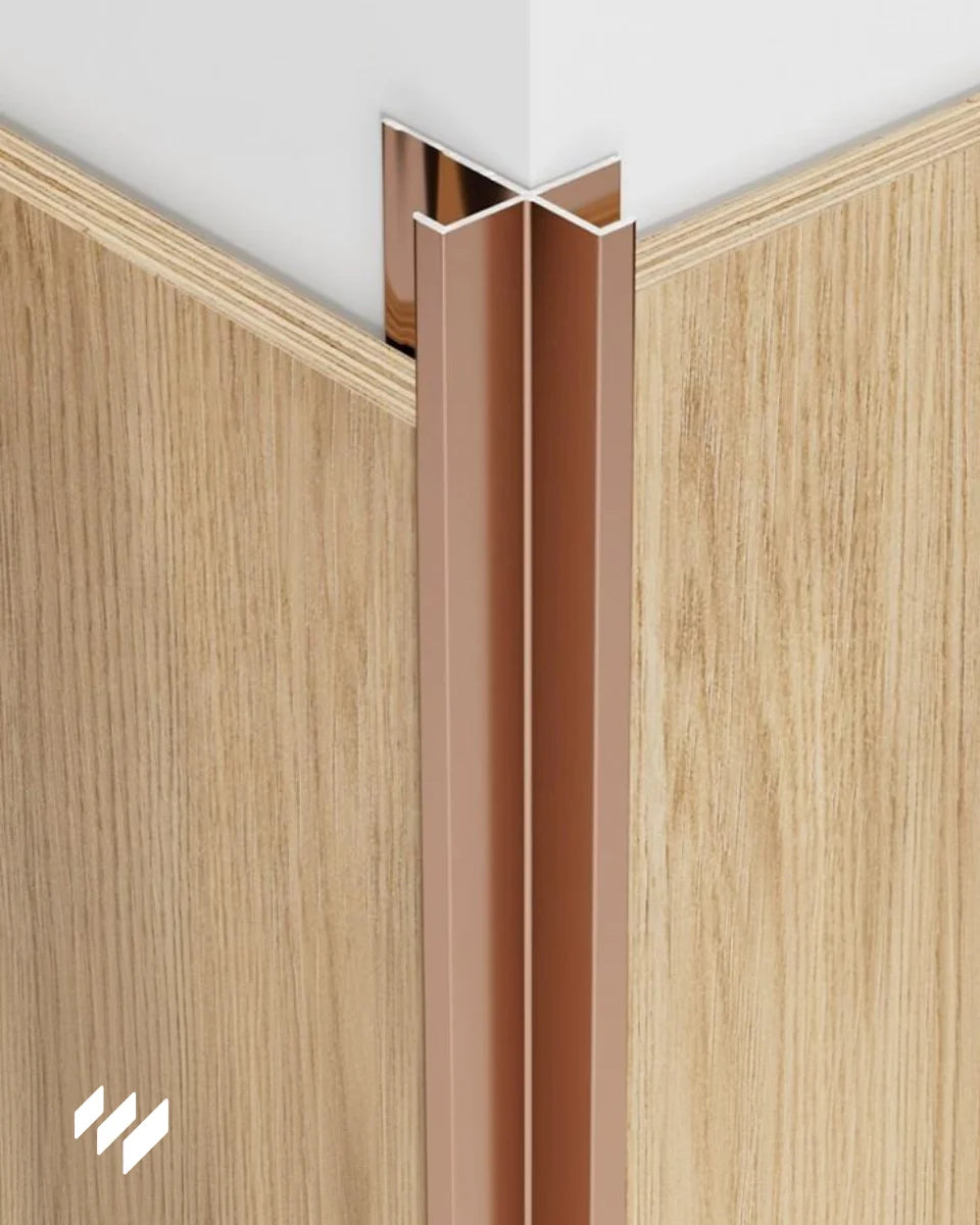 Perfil de Esquina Exterior de Aluminio con Rebaje en acabado oro rosa brillante instalado en una esquina con paneles decorativos, demostrando su integración estética y funcional para revestimientos pared de revestimientos pared.
