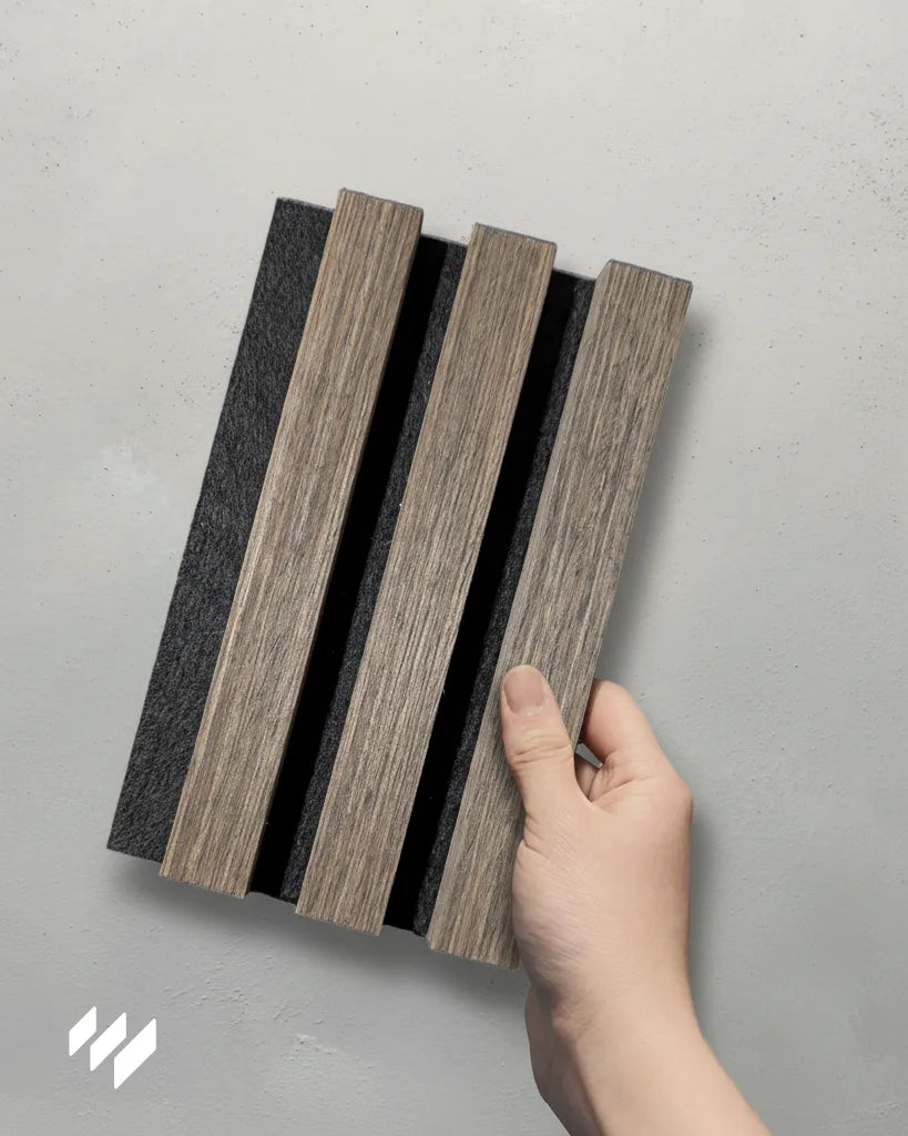 Muestra del Revestimiento de Pared 3D Palillería Acústica Roble Ahumado sostenida con una mano, producto de Revestimientos Pared.