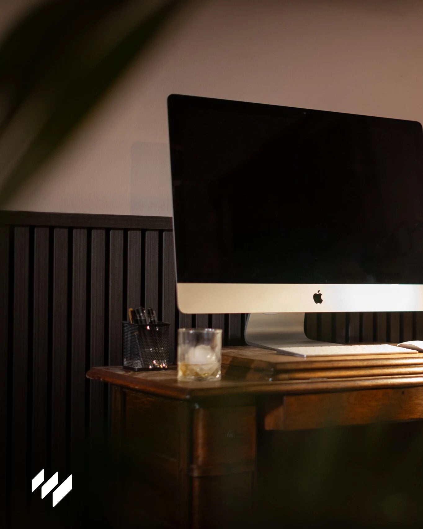 Panel de listones acústico Roble Negro de Revestimientos Pared realzando un espacio de oficina acogedor con escritorio de madera.