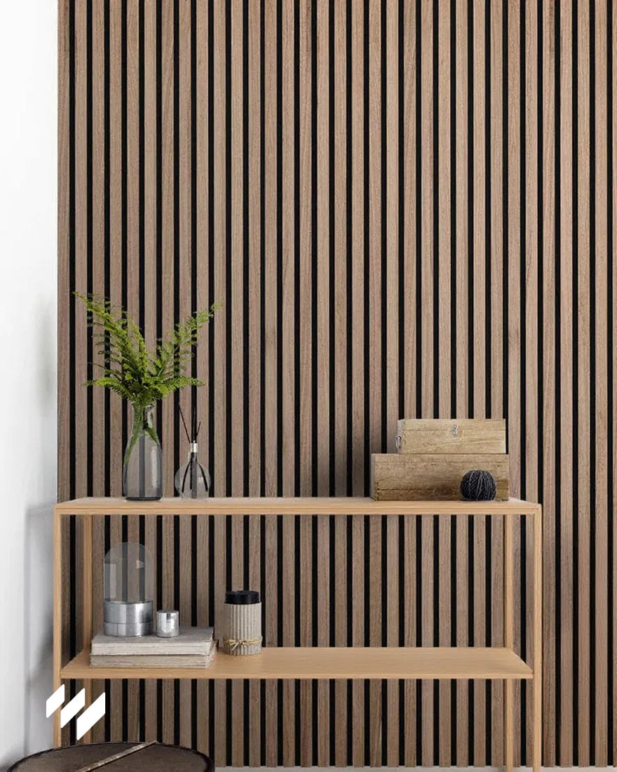 Panel acústico de listones en color Nogal Natural de Revestimientos Pared instalado detrás de una estantería de madera clara, en un rincón decorativo elegante y natural.