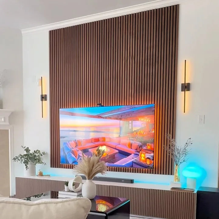 Salón con pared decorativa detrás del televisor utilizando el revestimiento de pared 3D Palillería Acústica en color Roble Ahumado de Revestimientos Pared, que aporta textura y sofisticación al espacio.