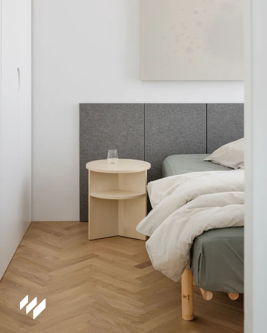 Cabecero de dormitorio decorado con tres paneles acústicos autoadhesivos de poliéster gris, instalados en vertical sobre pared blanca, diseño minimalista con suelo de madera natural — Revestimientos Pared.