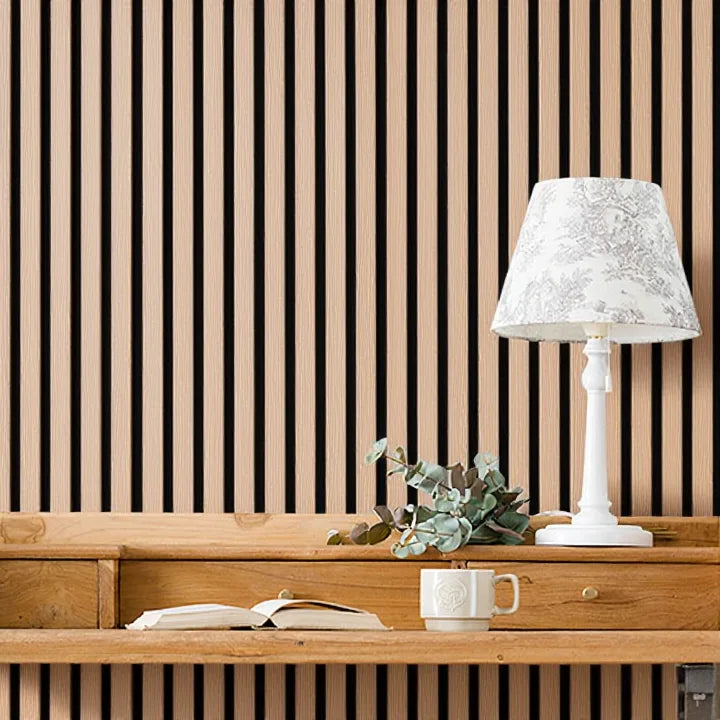 Vista de cerca de pared con panel acústico de listones en roble natural de revestimientos pared detrás de escritorio de madera y lámpara blanca.