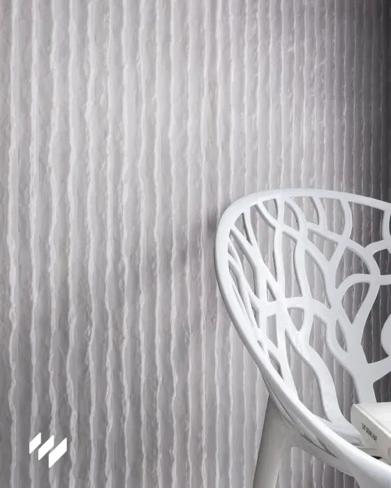 Inspiración de pared con Panel decorativo 3D de PU efecto piedra acanalada blanco de Revestimientos Pared, en un ambiente minimalista con silla de diseño, ofreciendo ideas para espacios contemporáneos.