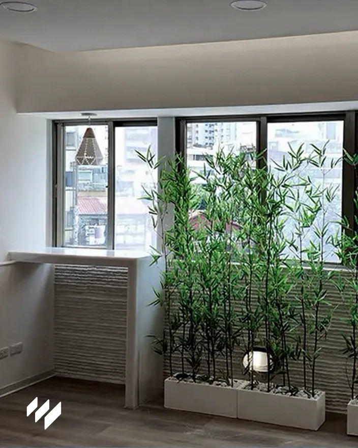 Espacio junto a la ventana decorado con Panel decorativo 3D de PU efecto piedra acanalada blanco de Revestimientos Pared, acompañado de plantas de bambú, ofreciendo ideas para ambientes frescos y naturales.