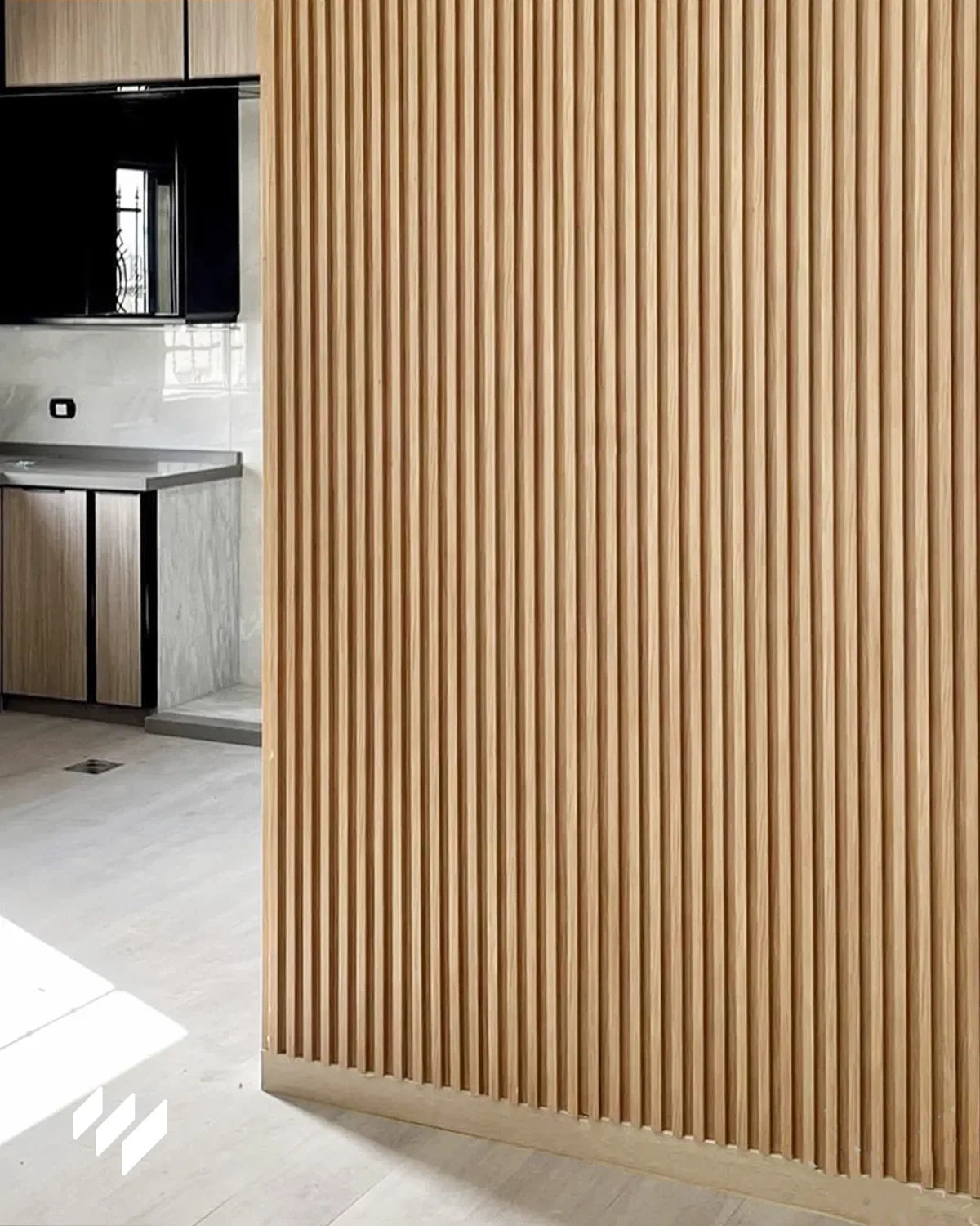 Revestimiento de pared de listones WPC Roble Miel separando cocina y salón en un espacio abierto de Segovia.