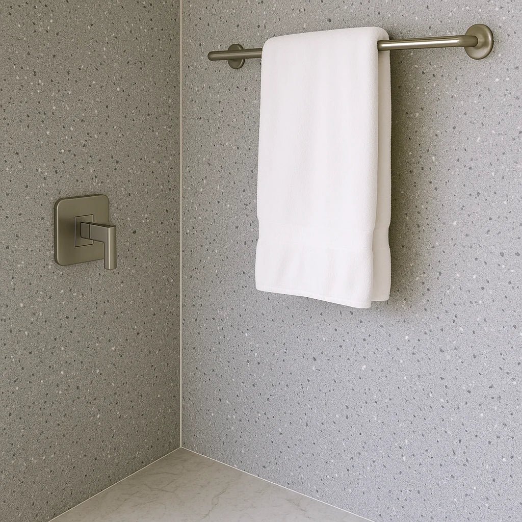 Panel SPC effecto terrazo gris instalado en una pared de baño, mostrando que elementos como toalleros deben fijarse directamente a la base estructural, no solo al panel decorativo.