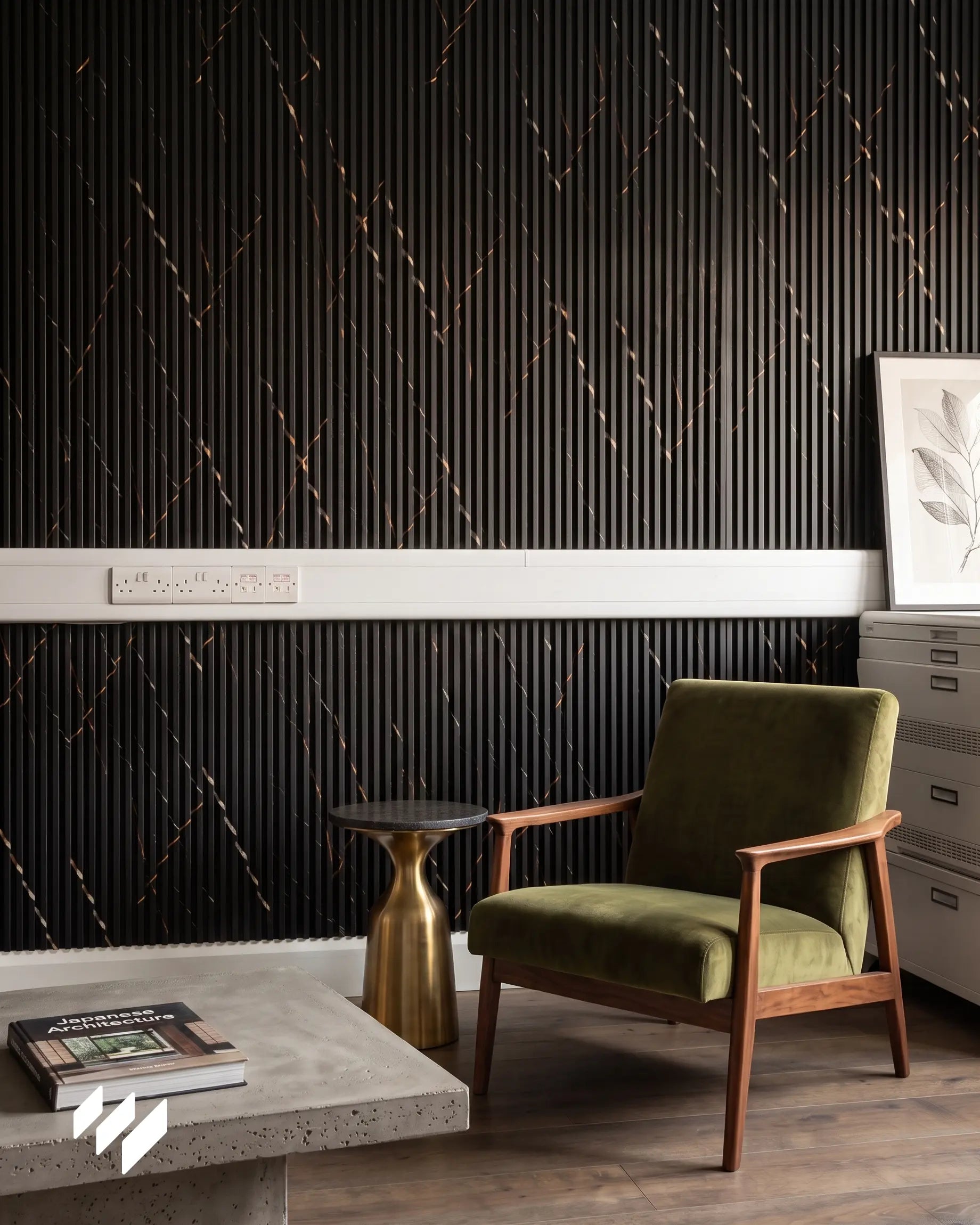 Pared decorada con revestimiento de listones WPC Mármol Portoro Oro en una oficina de estilo retro en Madrid, con sillón verde, mesa auxiliar dorada, suelo de madera y enchufes integrados sobre la pared.