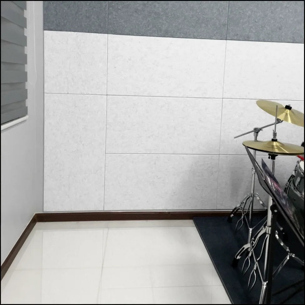 Paneles acústicos de poliéster blanco instalados en una sala de música con batería, utilizados para insonorizar un parking de 45 m² transformado ocasionalmente en salón para reuniones. El cliente destaca la notable reducción del eco y su función decorativa tras instalar 15 unidades, logrando un cambio sorprendente y muy satisfactorio.