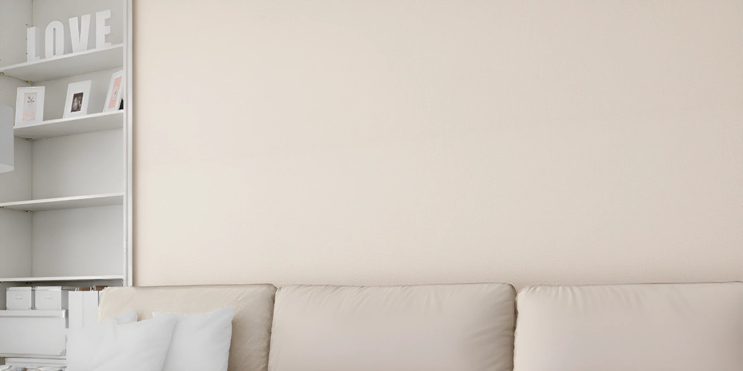 Salón con sofá claro y estantería blanca; la pared del fondo es lisa y beige, antes de instalar el revestimiento. PC View