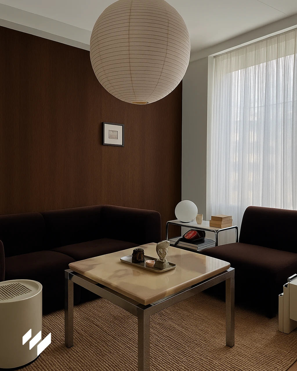 Salón moderno con pared revestida en Roble Nocturno WPC, sofá minimalista color oscuro y gran lámpara colgante bajo luz natural.