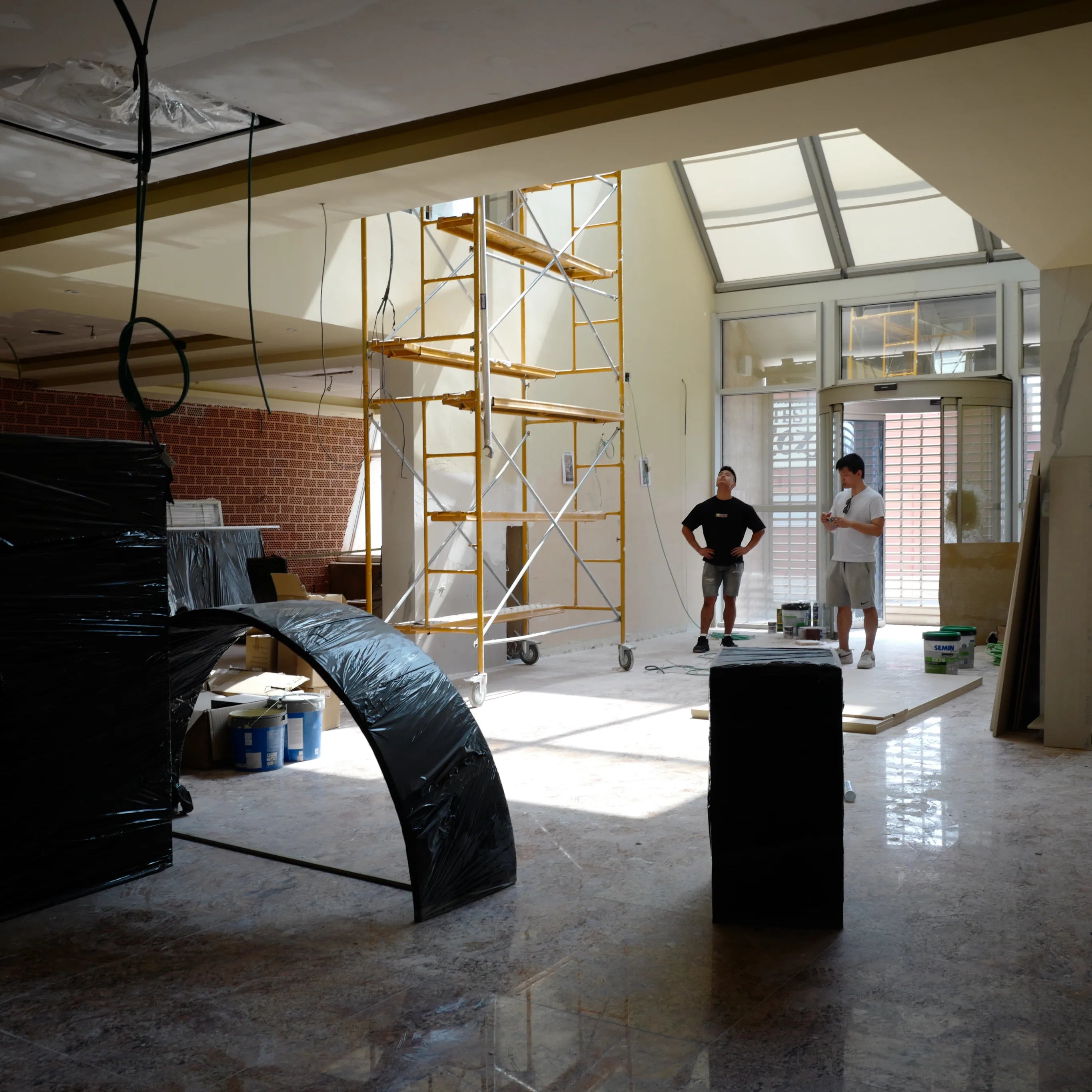 Equipo de MainDesign Studio e INKU Sushi evaluando un nuevo local en Valencia, con luz natural y andamios, 2024.