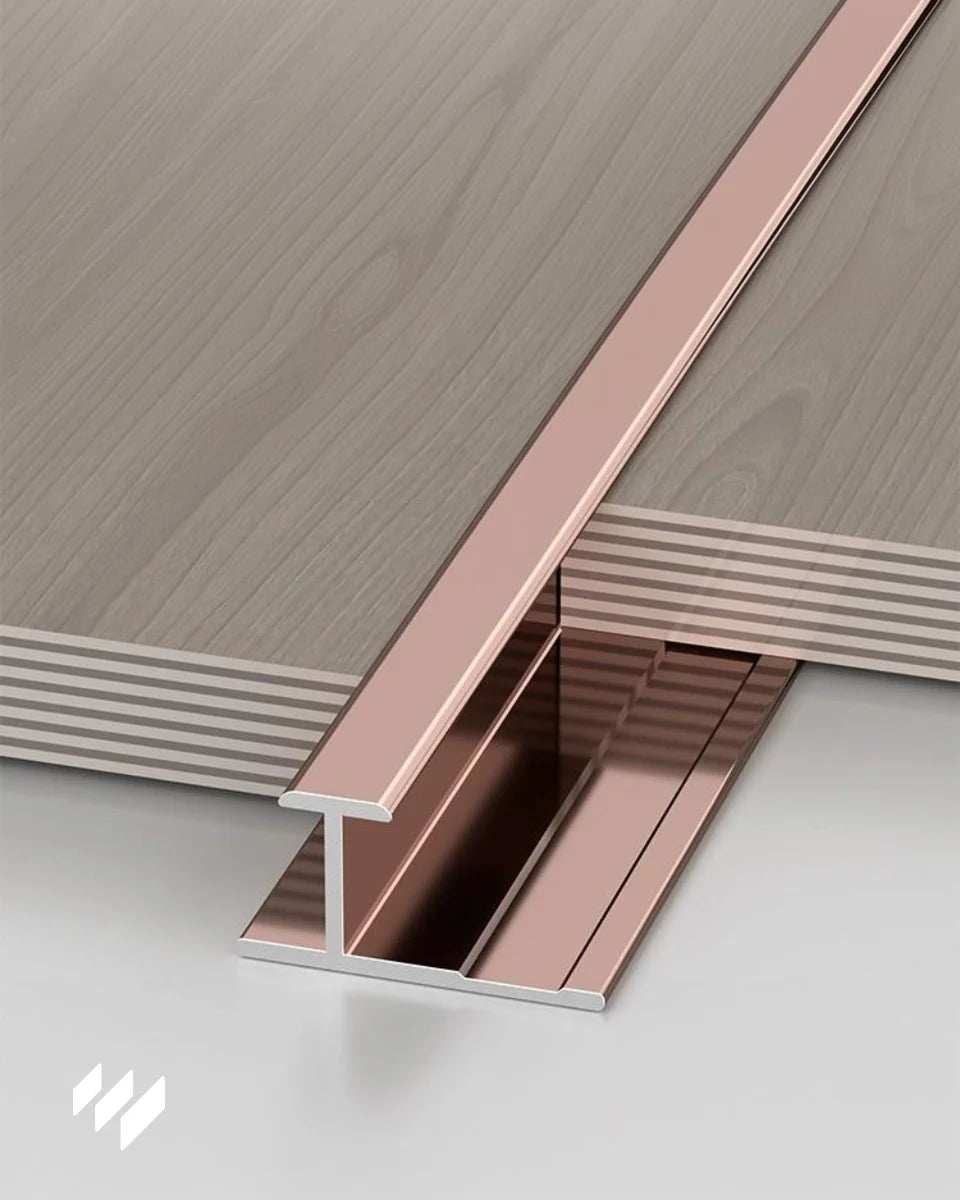 Detalle del perfil de unión en H de aluminio en acabado oro rosa brillante para paneles de revestimientos pared, mostrado en una instalación horizontal con acabado limpio y preciso.