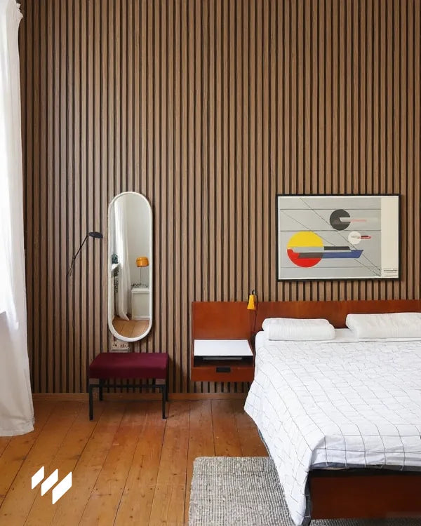 Dormitorio decorado con panel acústico de listones color Nogal Natural de Revestimientos Pared, creando un ambiente cálido y contemporáneo.