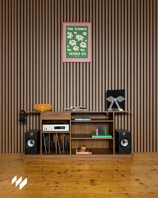 Mueble de estilo vintage frente al panel acústico de listones Nogal Natural de Revestimientos Pared, resaltando la integración del diseño con elementos decorativos modernos.