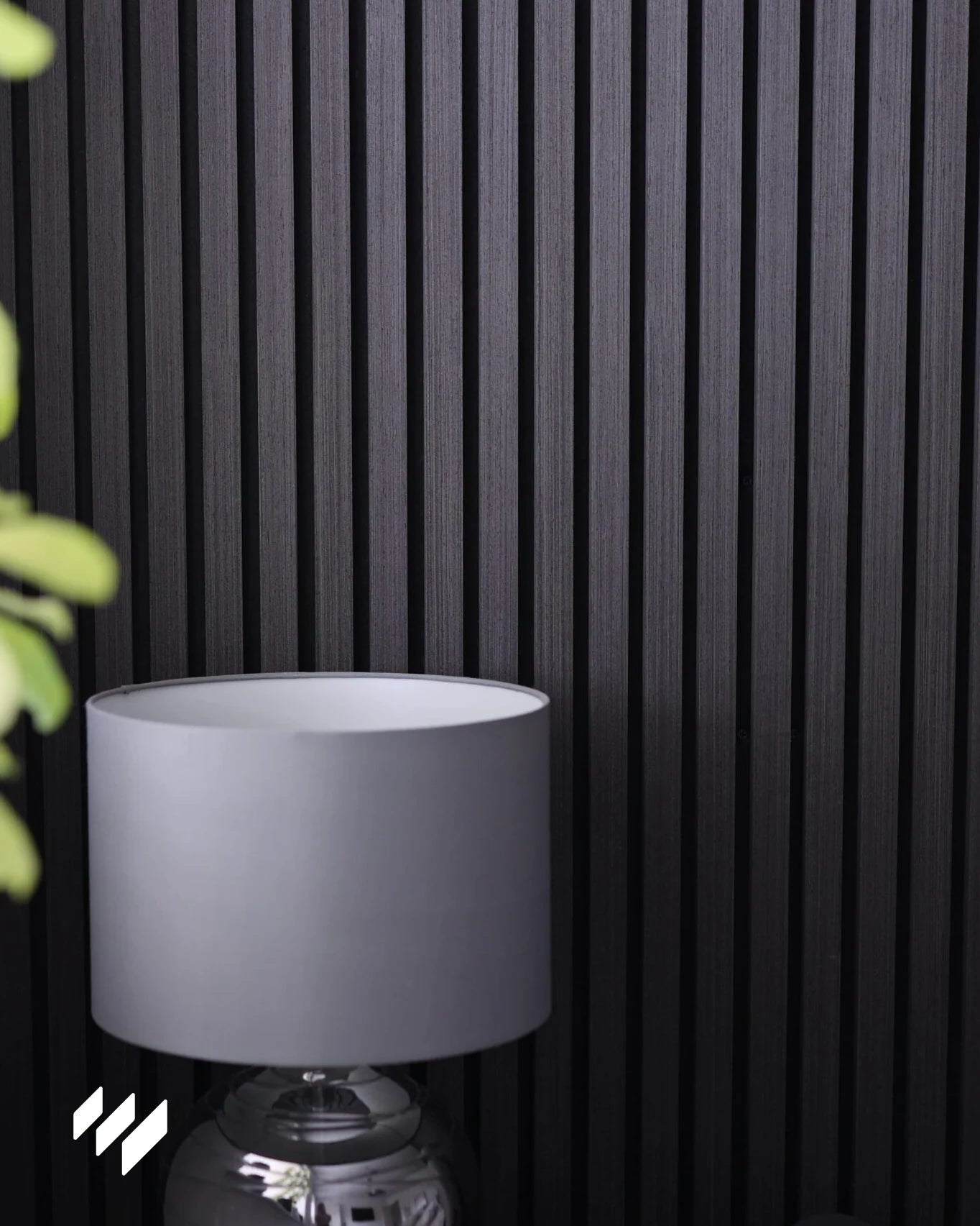 Panel acústico Roble Negro de Revestimientos Pared instalado en pared interior moderna, acompañado de una lámpara decorativa.