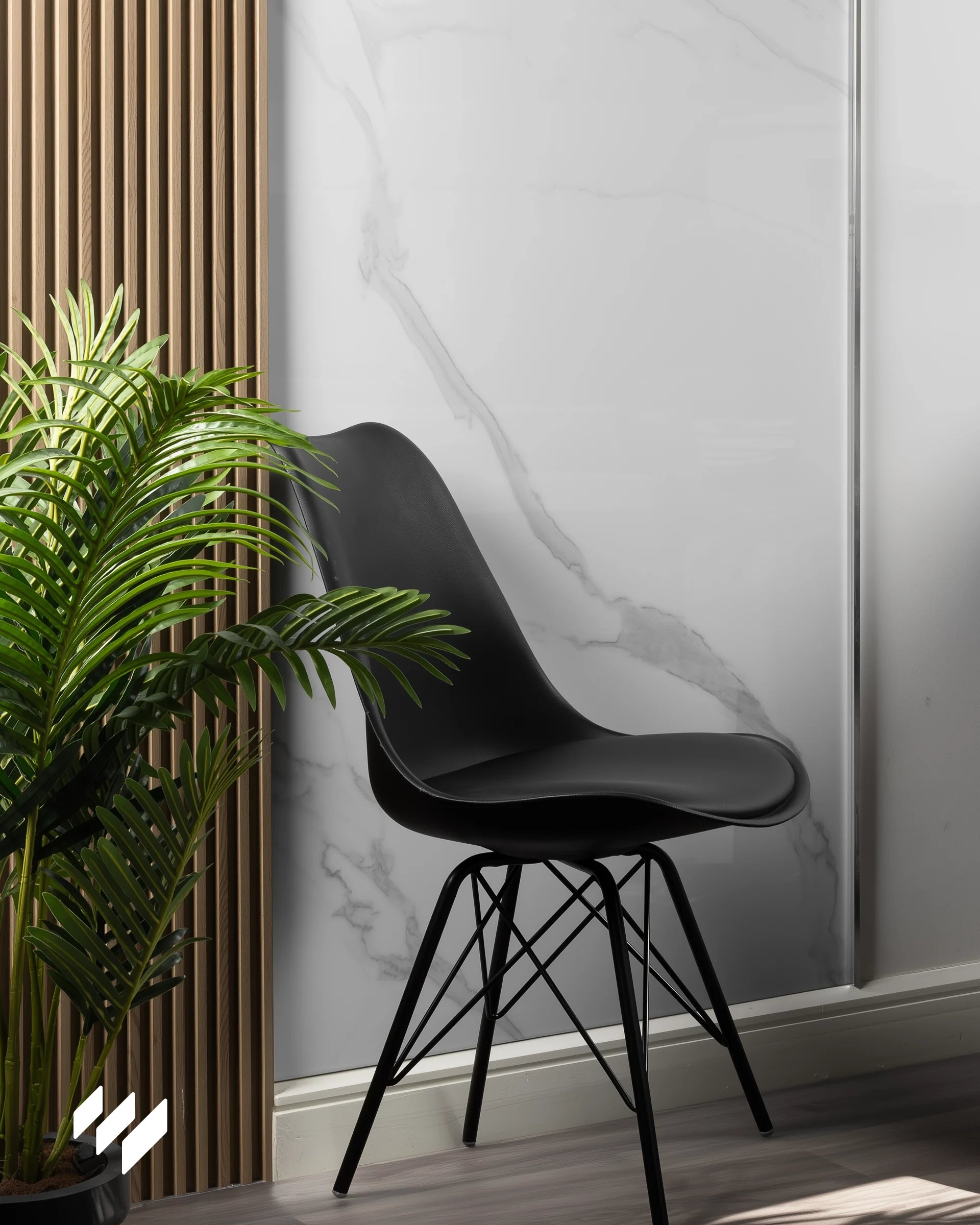 Pared revestida con panel WPC efecto mármol Calacatta Blanco de Revestimientos Pared junto a listones de madera y silla negra moderna.