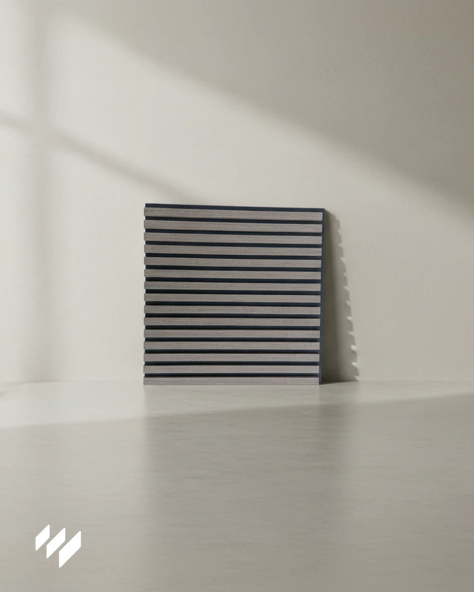 Vista frontal del panel acústico autoadhesivo Roble Ahumado con dos bordes negros visibles de fieltro PET, apoyado sobre una superficie neutra con iluminación natural.