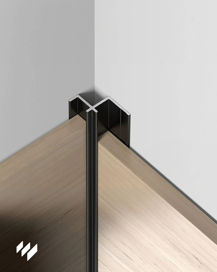 Perfil de esquina interior de aluminio negro mate instalado en un ángulo interior sobre paneles decorativos, aplicación real de revestimientos pared