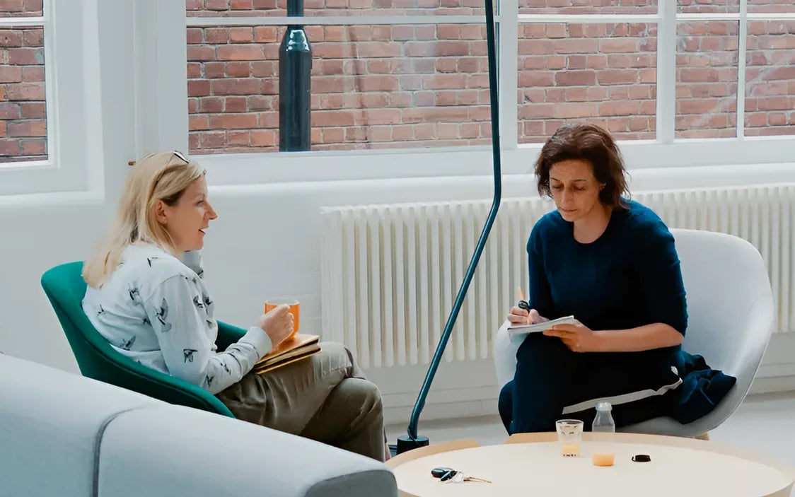 Dos personas conversan sobre la elección de paneles de pared en una sala luminosa y moderna.