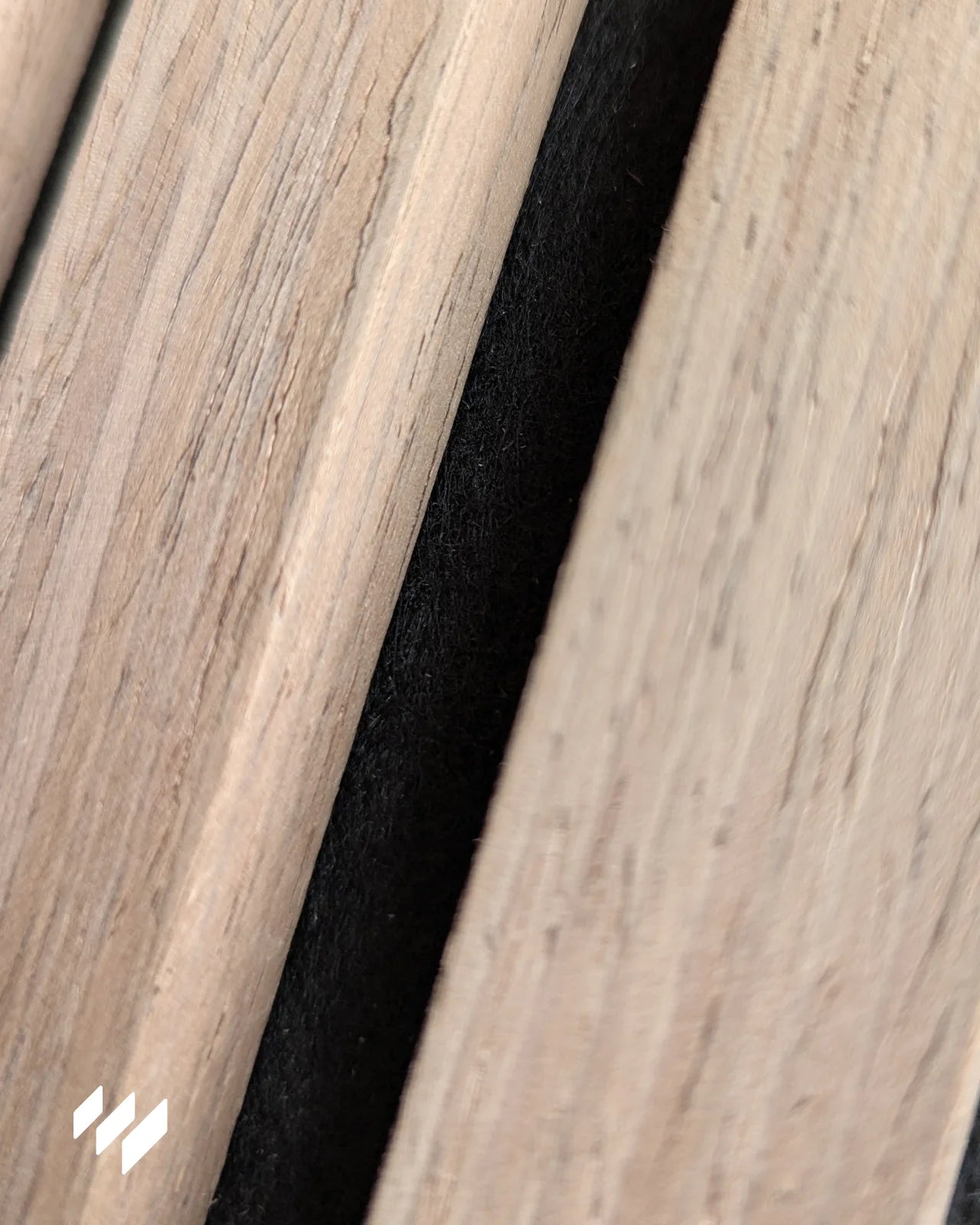 Detalle en primer plano del acabado en madera Nogal Natural y fieltro negro PET del panel acústico.