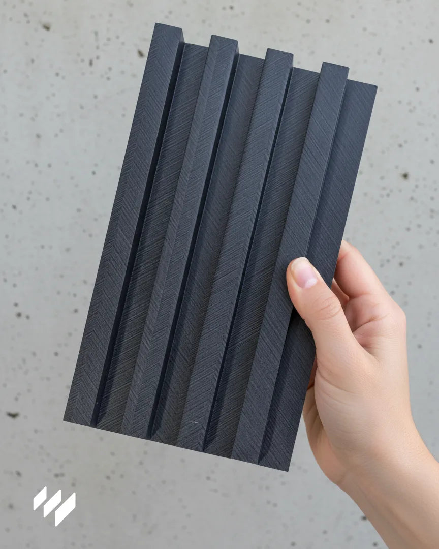 Muestra del revestimiento de pared de listones WPC Gris Carbón Espiga de Revestimientos Pared, con patrón geométrico y textura moderna en gris oscuro.