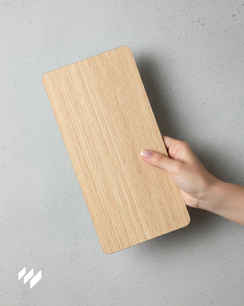 Muestra del revestimiento de pared WPC efecto madera Roble Natural sostenida con una mano sobre fondo gris claro — Revestimientos Pared.