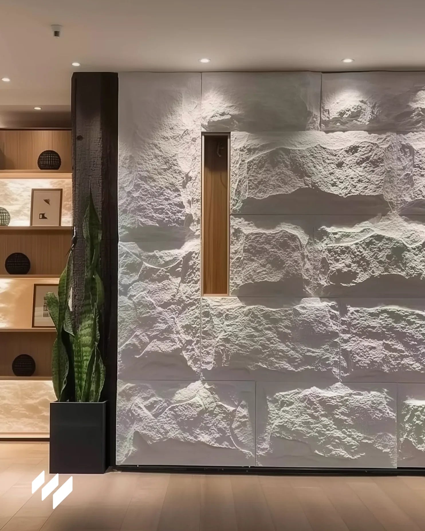 Instalación del Panel Piedra PU Blanco Caliza de Revestimientos Pared en pared interior moderna con iluminación cálida y estanterías decorativas.