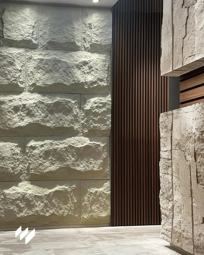 Panel Piedra PU Blanco Caliza de Revestimientos Pared instalado en pasillo moderno con contraste de listones de madera y luz ambiental.
