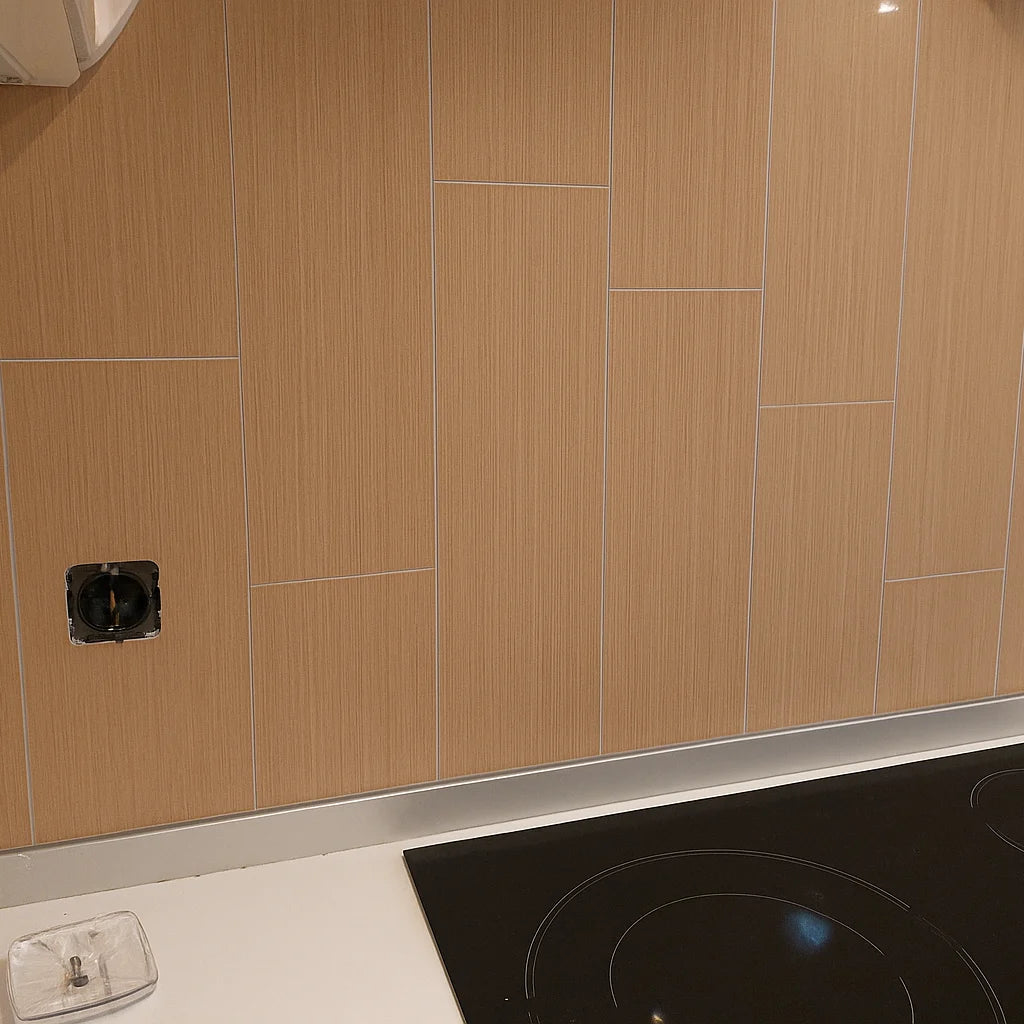 Revestimiento de pared en cocina detrás de la encimera, utilizando panel SPC efecto madera cerámica de textura lineal clara, con juntas visibles y acabado limpio.