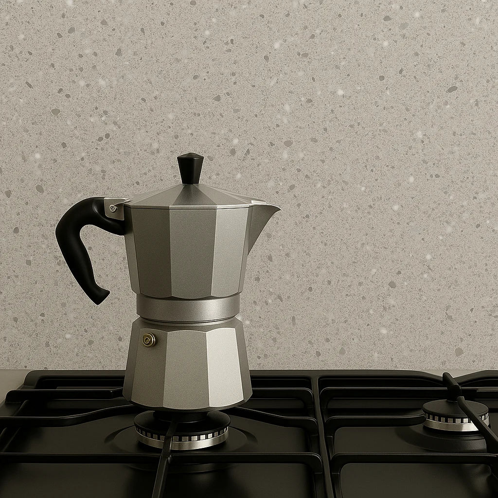 Panel SPC effecto terrazo gris instalado en la pared de una cocina, manteniendo una distancia segura de aproximadamente 15 cm de una estufa de gas encendida.