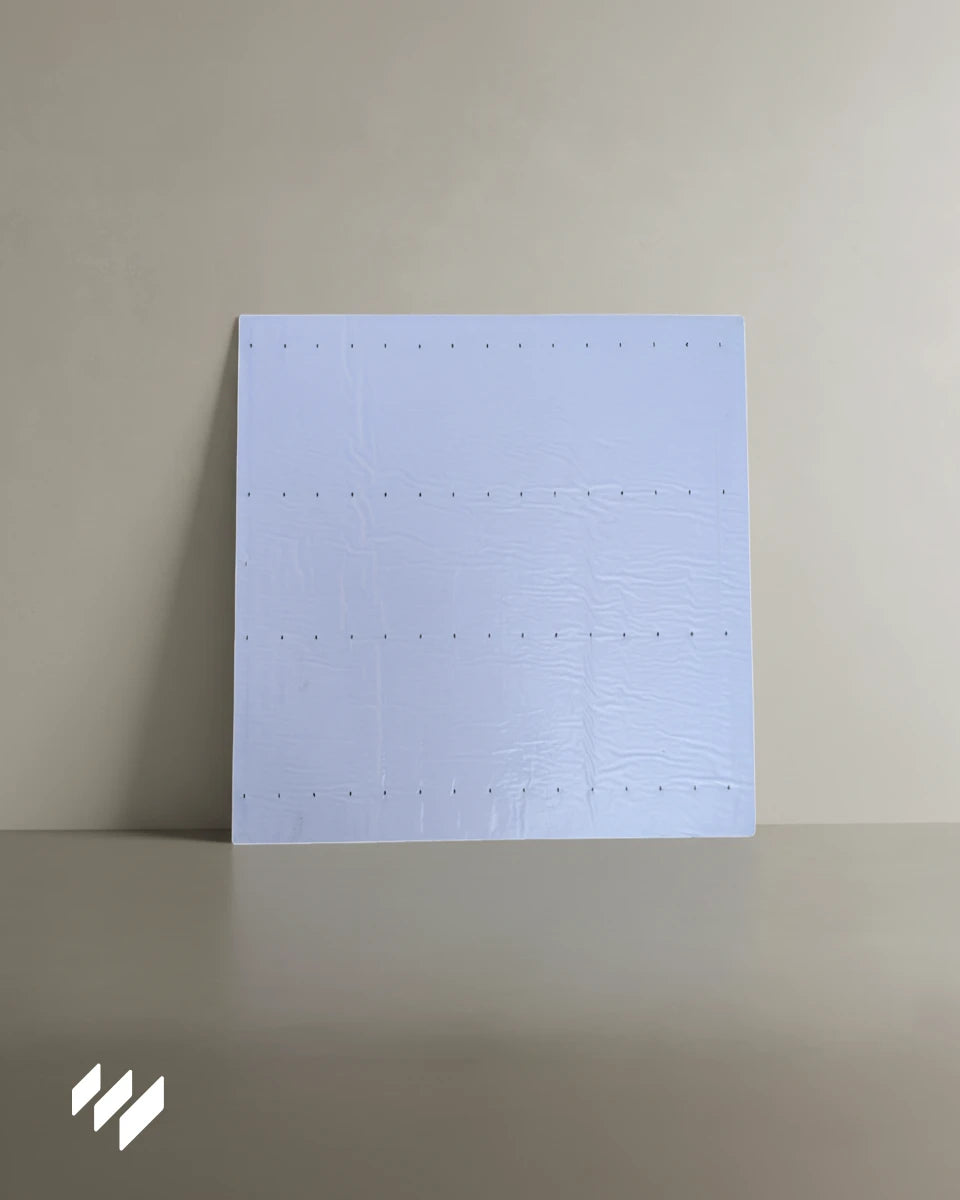 Parte trasera del panel acústico autoadhesivo con superficie blanca protectora y puntos de fijación visibles antes de retirar el adhesivo.