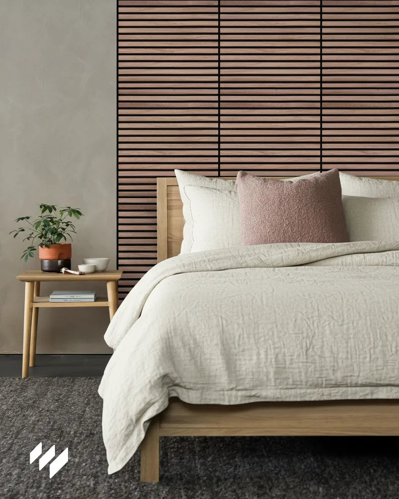 Revestimiento de pared acústico autoadhesivo Nogal Natural instalado en dormitorio estilo escandinavo con cama de madera y ropa de cama beige.